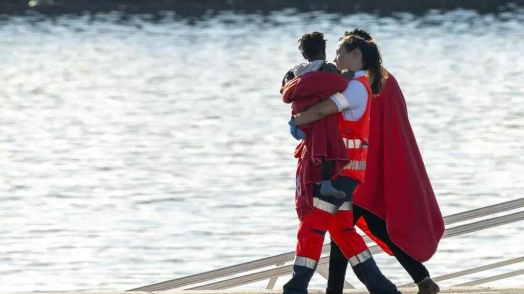 Trabajadora de la Cruz Roja lleva en brazos a un bebé tras la llegada de una patera a Arrecife.