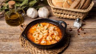 Cazuela con gambas al ajillo acompañadas de pan.