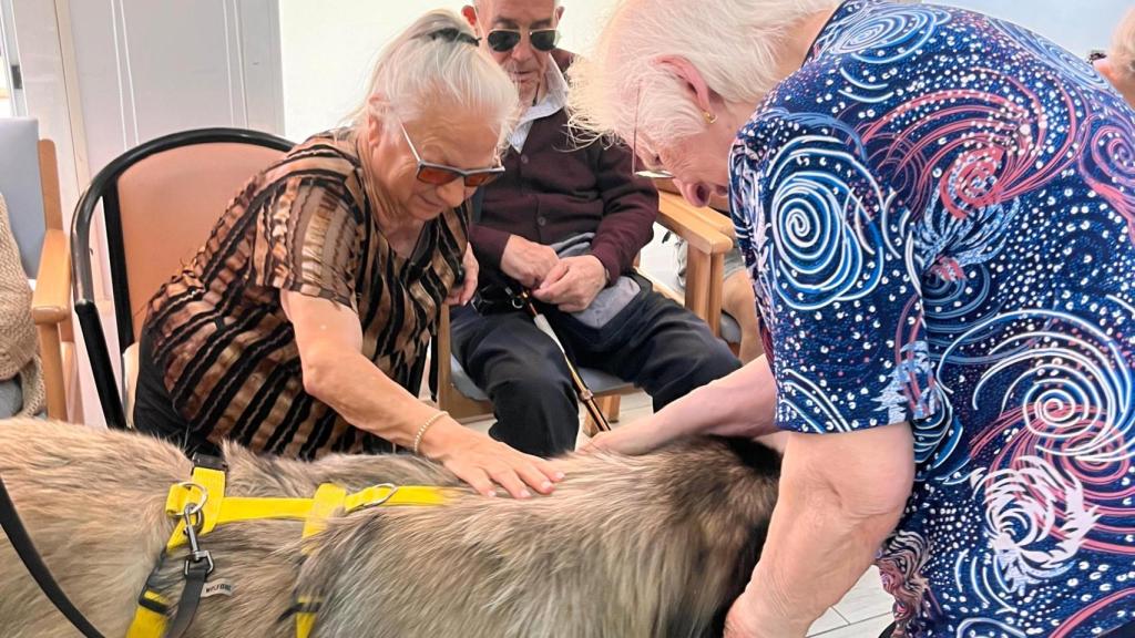 Dos señoras acariciando a Chakala en el Centro de día El Val.