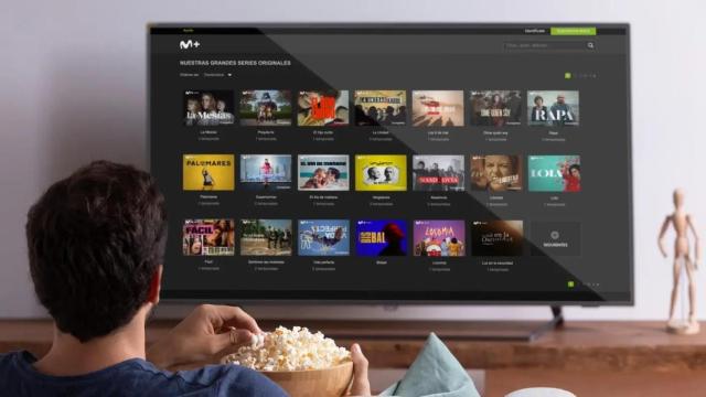 Un hombre comiendo palomitas mientras ve la oferta de Movistar Plus+ en su televisor.