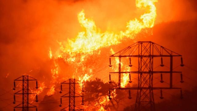 Redes eléctricas de alta tensión delante de un incendio forestal.