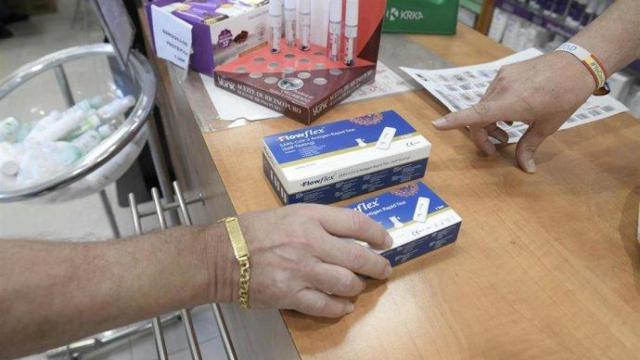 Un farmacéutico enseña un test de antígenos de detección del COVID-19 en una farmacia.