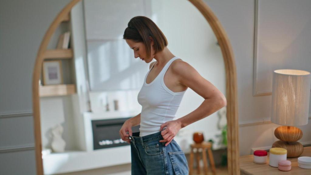 Imagen de archivo de una mujer preocupada por su peso frente al espejo.