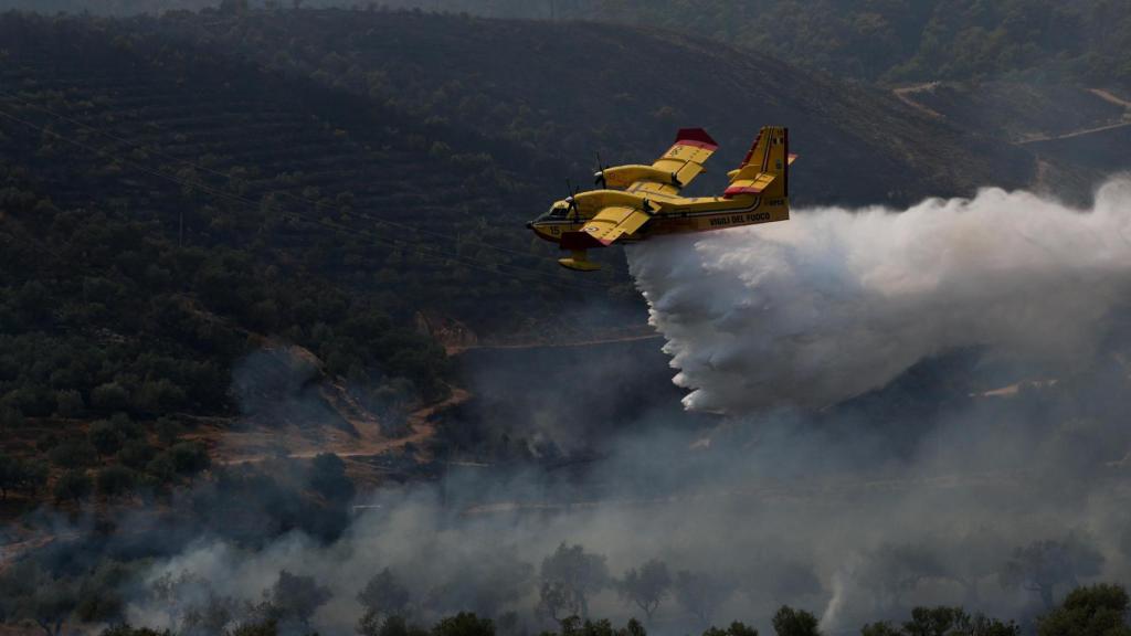 Un avión canadiense de extinción de incendios (CanadAir) italiano arroja agua para contener un incendio forestal que continúa ardiendo en Delvina, Albania, el 13 de agosto de 2025.