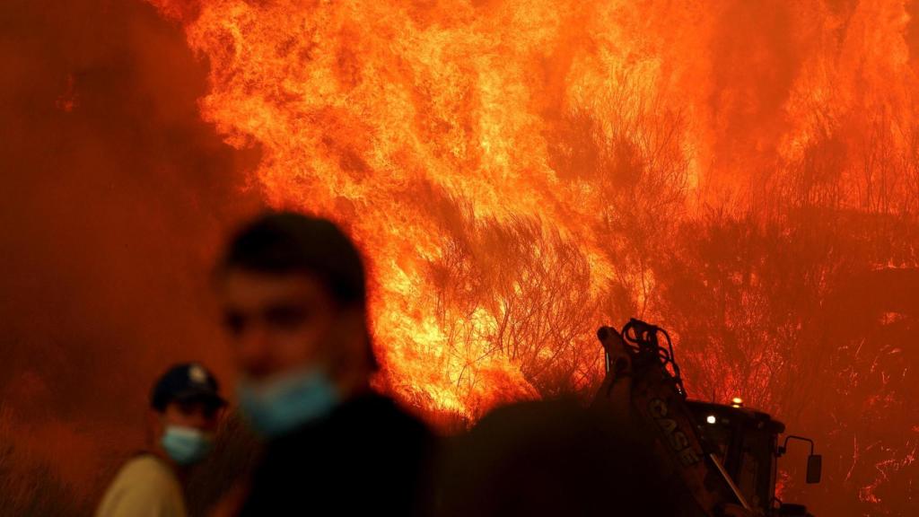 Personas observan cómo un incendio forestal se aproxima a Trancoso, Portugal, el 13 de agosto de 2025.
