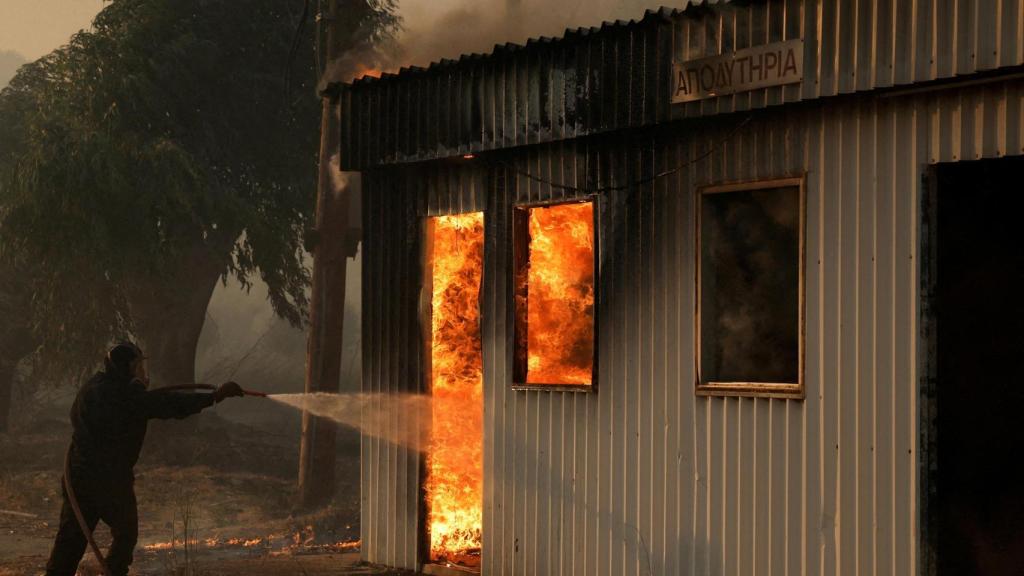 Un bombero trabaja para extinguir un fuego en un edificio durante un incendio forestal, en Sichaina, cerca de Patras, Grecia, el 13 de agosto de 2025.