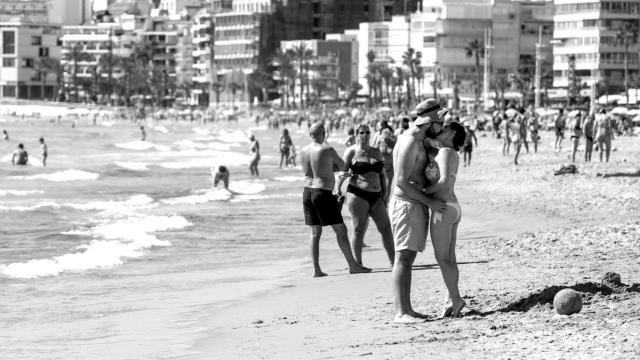 Una pareja en bañador se besa en la playa de Poniente