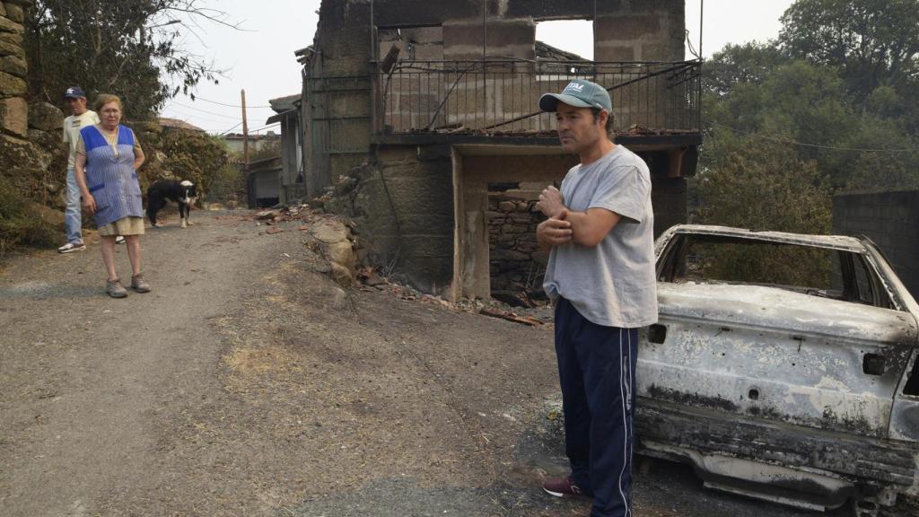 Samuel, vecino de A Caridade (Cualedro) delante de su casa destruída por el fuego, igual que propiedades de sus vecinos Dosinda y José Antonio