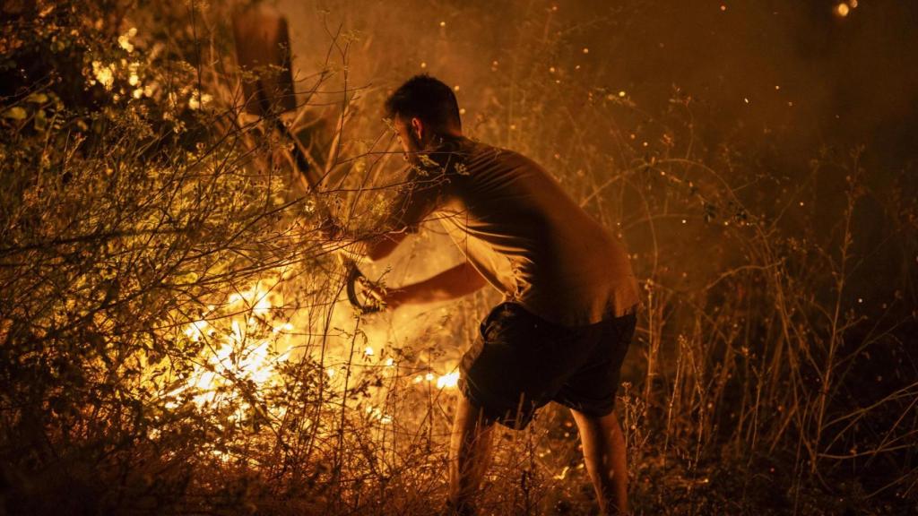 Un vecino intenta apagar el fuego en el incendio forestal de A Rúa (Orense).
