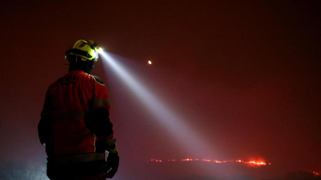 Un bombero usa una linterna mientras trabaja para extinguir un incendio forestal en As Fermosas (Orense)