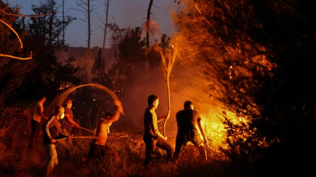 Los vecinos usan ramas de árboles para intentar extinguir las llamas de un incendio forestal en Vilar de Condes (Orense).