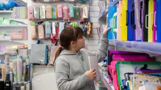 Niña eligiendo cuadernos en una papelería