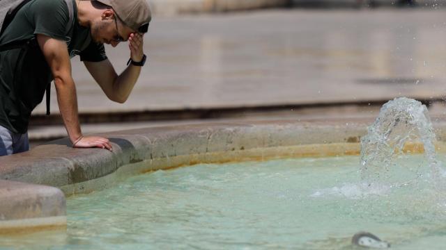 Un hombre echándose agua en una fuente en una imagen de archivo.