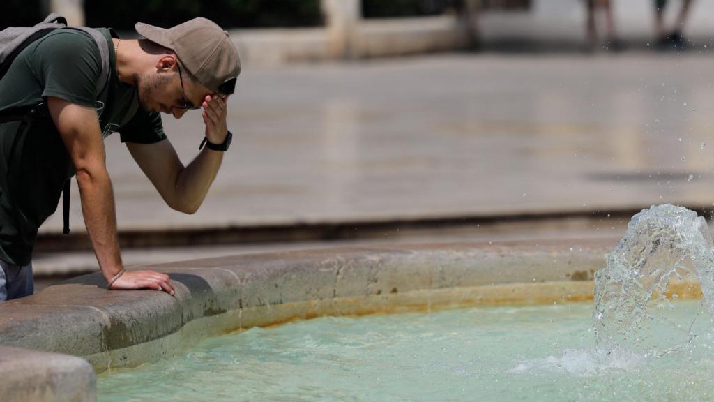 Un hombre echándose agua en una fuente en una imagen de archivo.