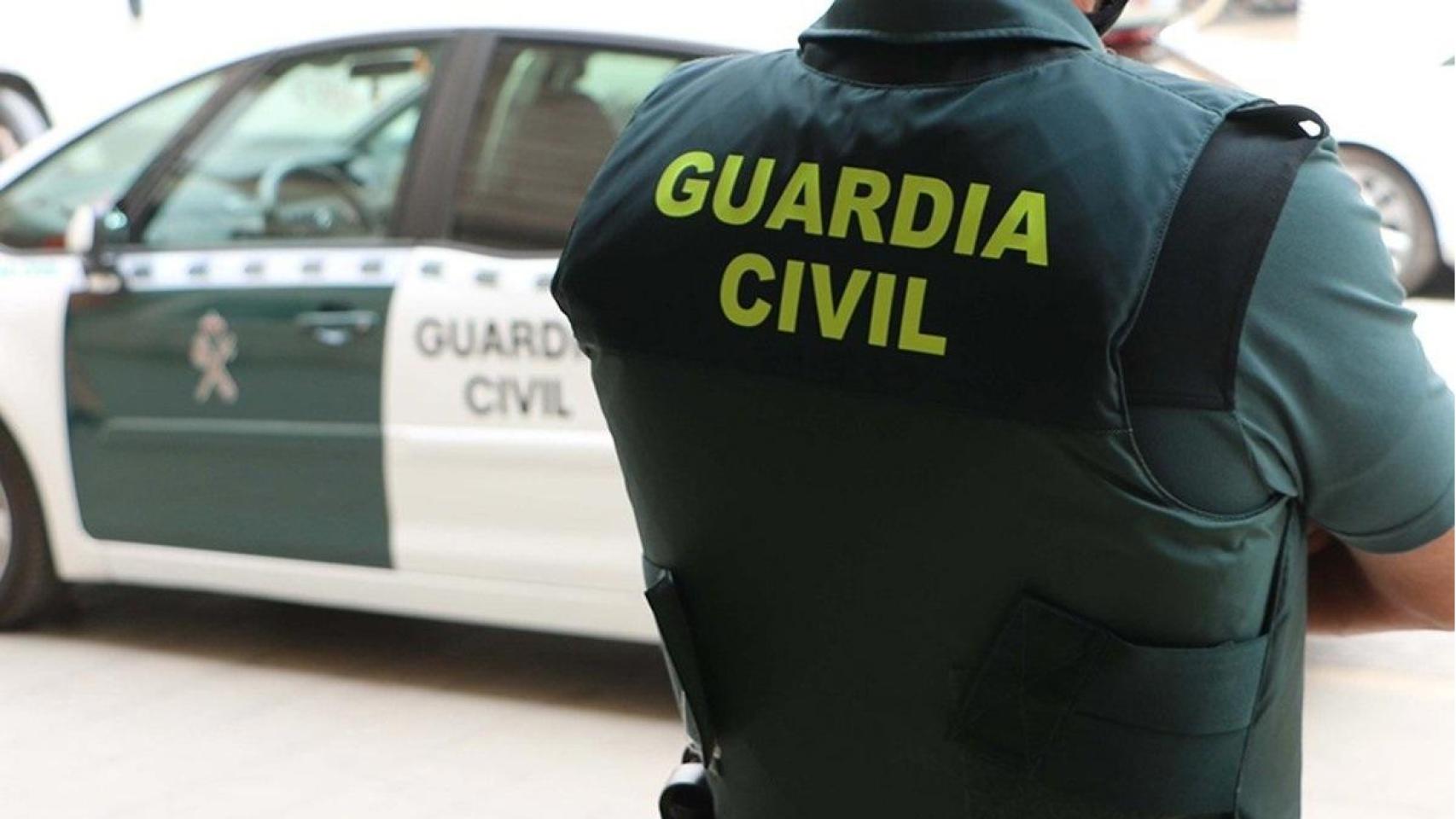 Un agente de la Guardia Civil, de espaldas, junto a un vehículo oficial del Instituto Armado