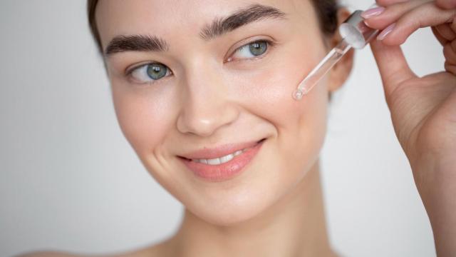 Foto de una mujer aplicándose suero facial.