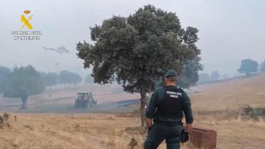 Un guardia civil vigila los trabajos de los buldozers y del helicóptero en el fuego de Colmenar.