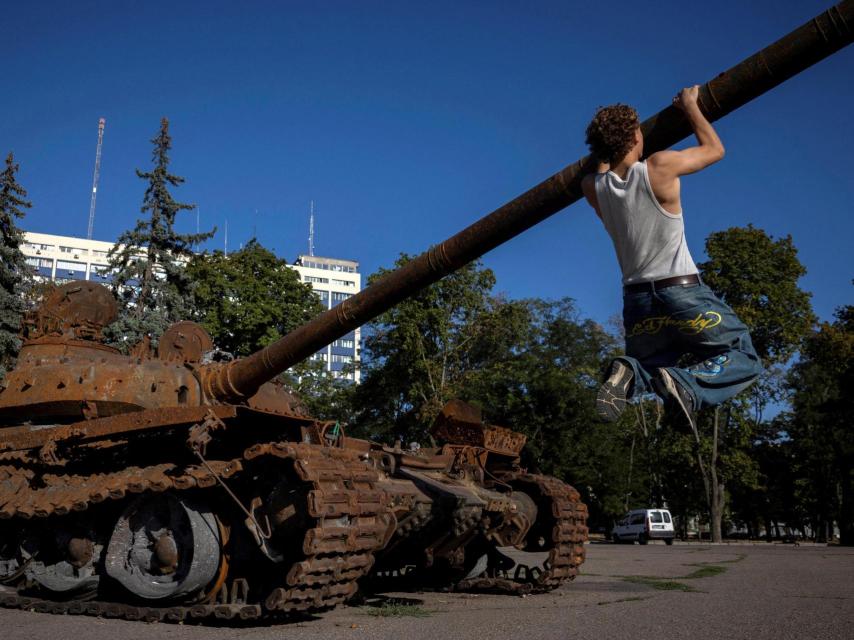 Un hombre se sube al cañón de un tanque ruso T-72 capturado, expuesto en Odesa el 12 de agosto de 2025.
