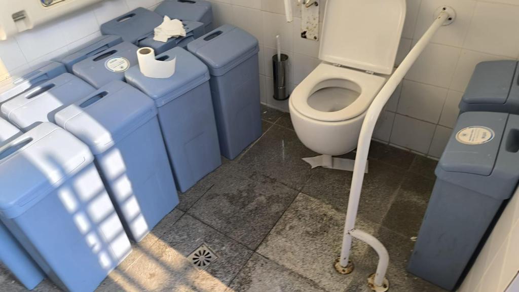 Estado de uno de los aseos con contenedores higiénicos acumulados y papel en el suelo, la mañana de este miércoles.