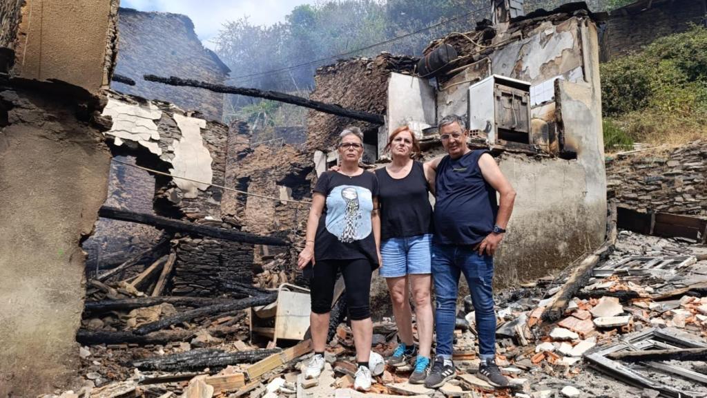 Antonio, frente a los restos humeantes de su casa en Lusío, junto a sus hermanas Beni (i) y Toña (d)