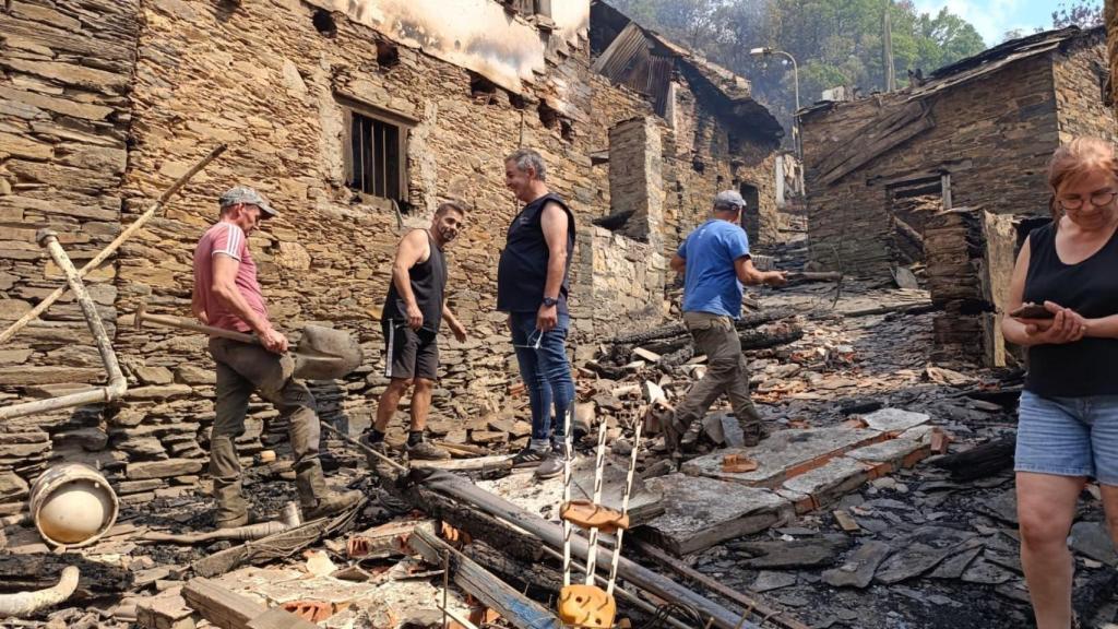 Antonio conversa con varios vecinos que buscan fugas de agua en las casas quemadas en Lusío.