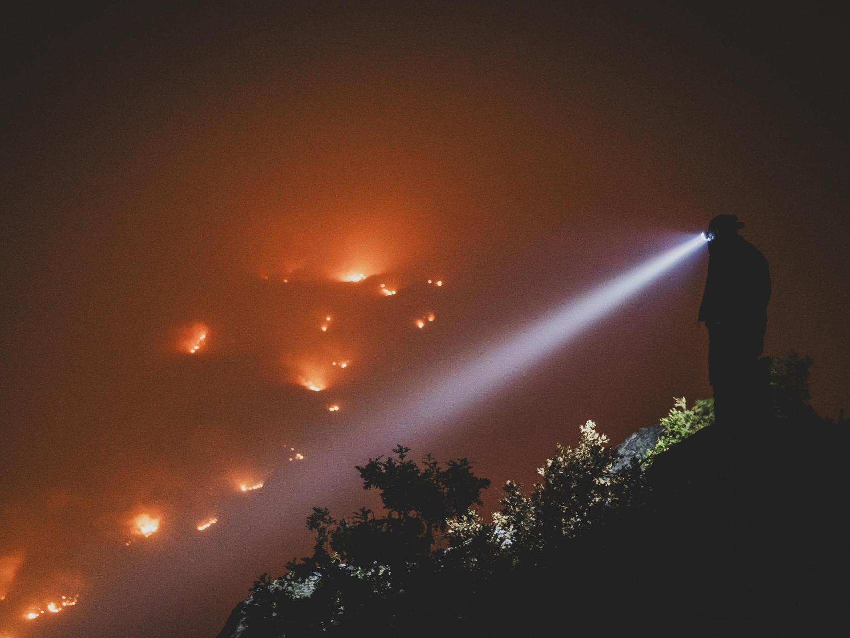Un voluntario en lo alto de la colina ve la devastación del fuego.