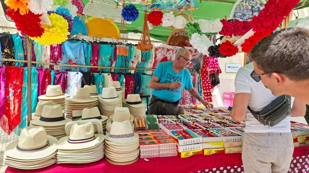 Un hombre comprando en el puesto de Paco en calle Larios durante la Feria de Málaga.