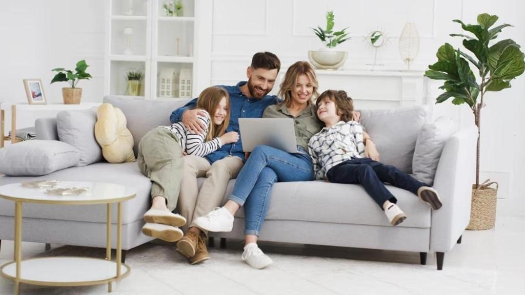 Una familia sentada en un sofá, mirando un ordenador