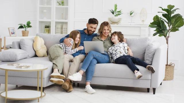 Una familia sentada en un sofá, mirando un ordenador