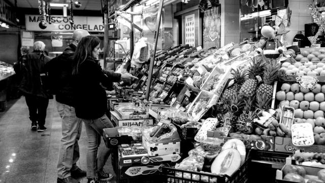Varias personas hacen compras de última hora en un mercado