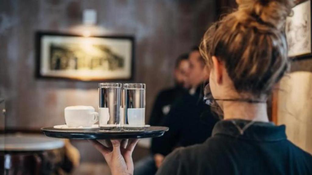 Imagen de una joven camarera llevando una bandeja.