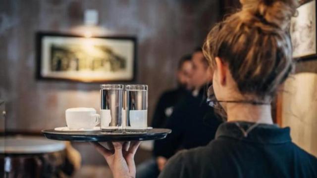 Imagen de una joven camarera llevando una bandeja.