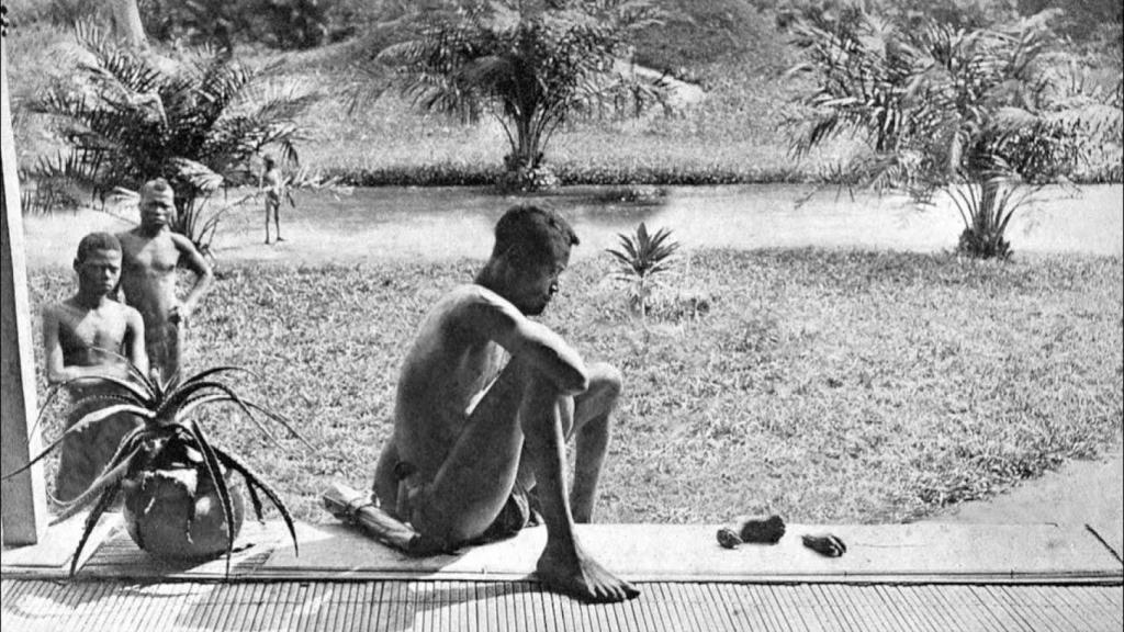 'Nsala de Wala en el distrito de Nsongo'. Nsala, sentado con la mano y el pie de su hija de cinco años, lo único que queda de un festín caníbal organizado por centinelas del caucho armados. Foto: Alice Seeley Harris / John Harris (concesión de ABIR)