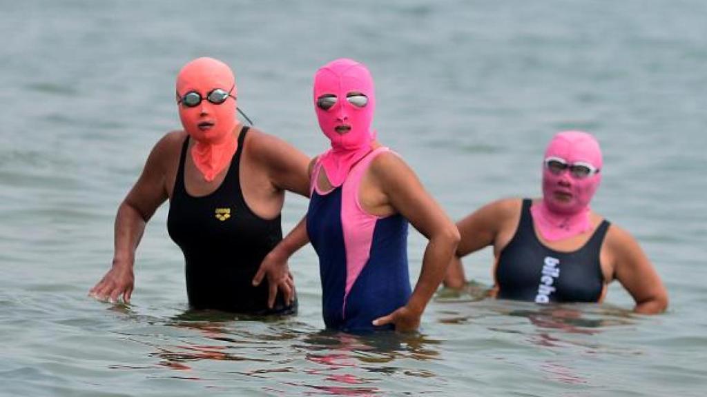Mujeres bañándose con sus respectivos 'facekinis'.
