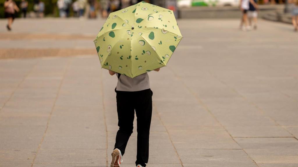 Una mujer se protege de la lluvia durante este verano.