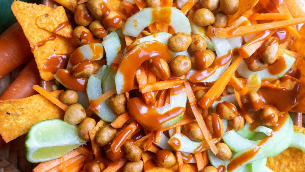 Nachos con zanahoria rallada, pepino, cacahuetes, lima y salsa chamoy.