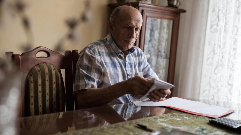 Un hombre mayor jubilado con el dinero de su pensión en un sobre.