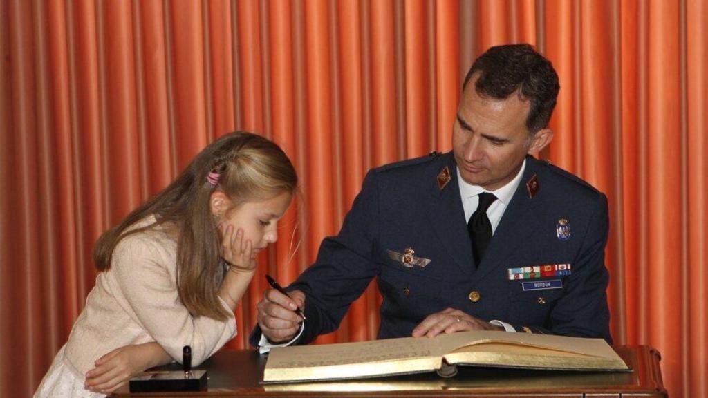 Felipe VI, cuando era príncipe de Asturias el 2 de mayo de 2014, firmando el libro de honor de la AGA, bajo la atenta mirada de su hija Leonor.