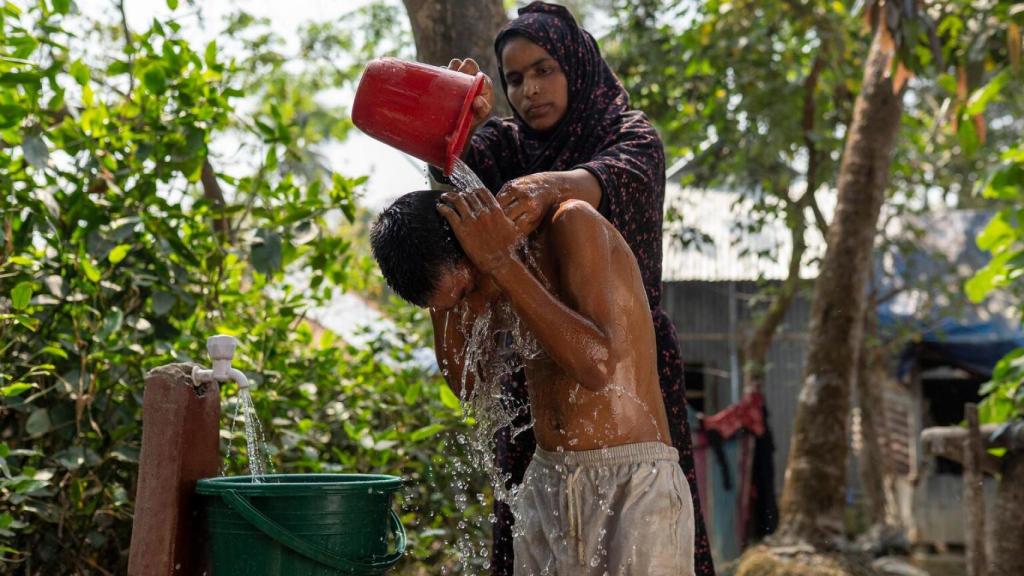 Una mujer lava a su hijo en Bangladés.