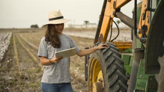 Joven agricultora junto al tractor.