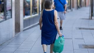 Foto de archivo de una señora mayor caminando con una bolsa.