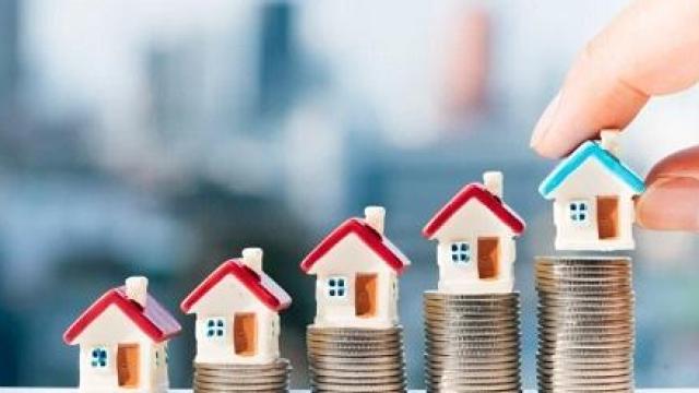 Imagen de unas casas sobre torres de monedas.