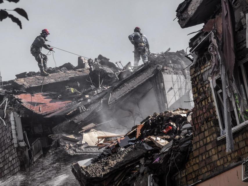 Rescatistas y bomberos trabajan en uno de los edificios residenciales bombardeados por Rusia esta madrugada, en Kiev, donde han muerto al menos 14 civiles.