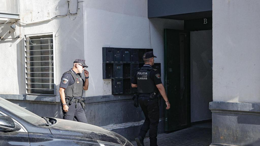 Dos agentes de la Policía Local acceden a la vivienda tras el asesinato a tiros a un hombre en Alaquàs (Valencia). Efe / Manuel Bruque