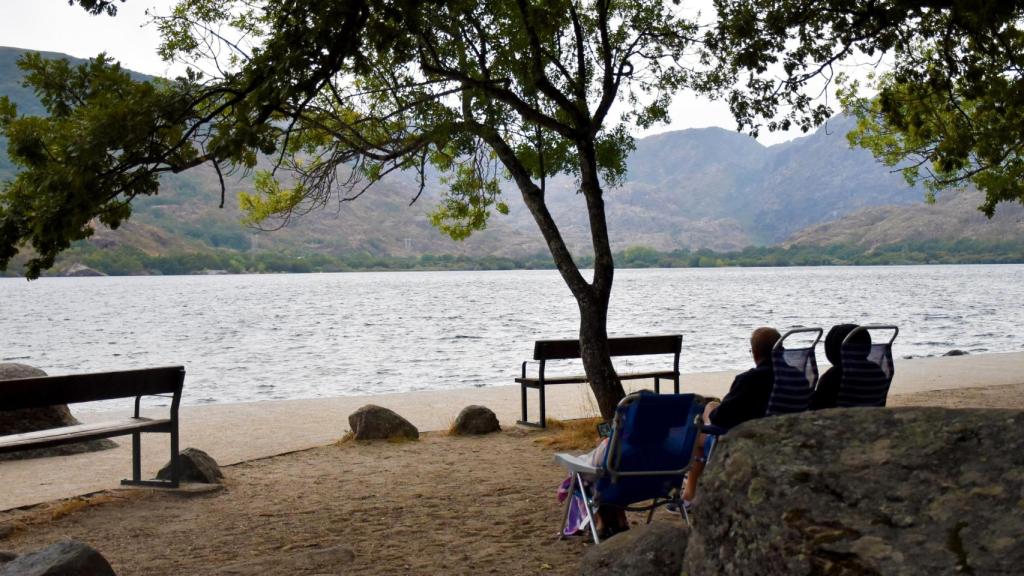Unos turistas admiran la vista del Lago de Sanabria desde sus sillas