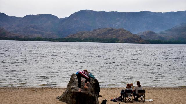 Unos visitantes disfrutan del Lago de Sanabria, que luce verde