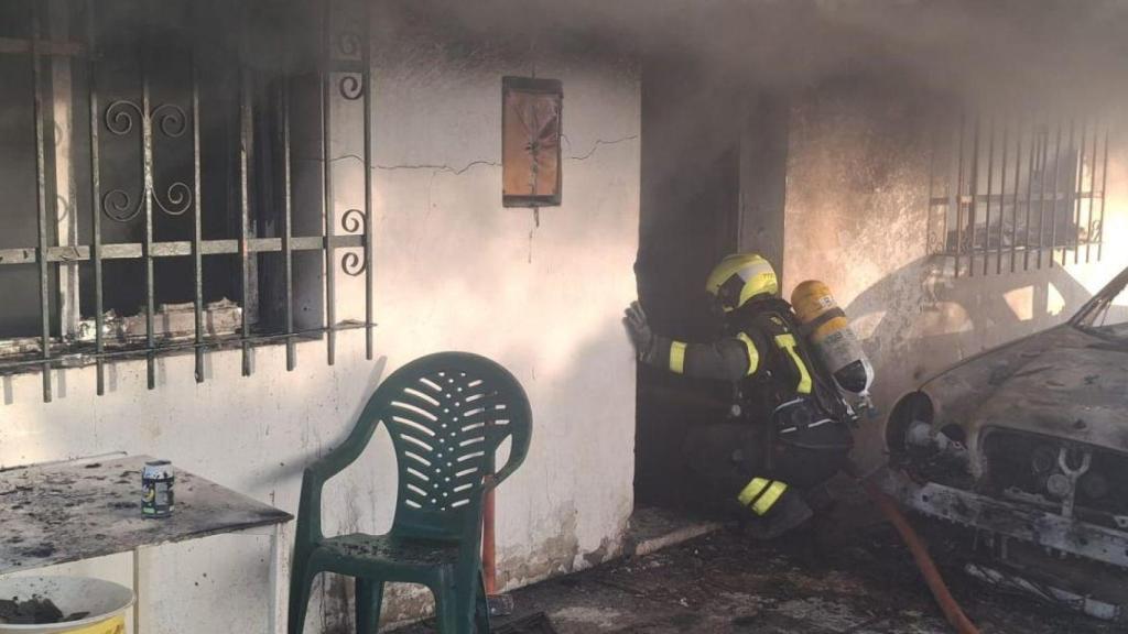 Un bombero intenta adentrarse en el interior de la vivienda calcinada en Cádiz.