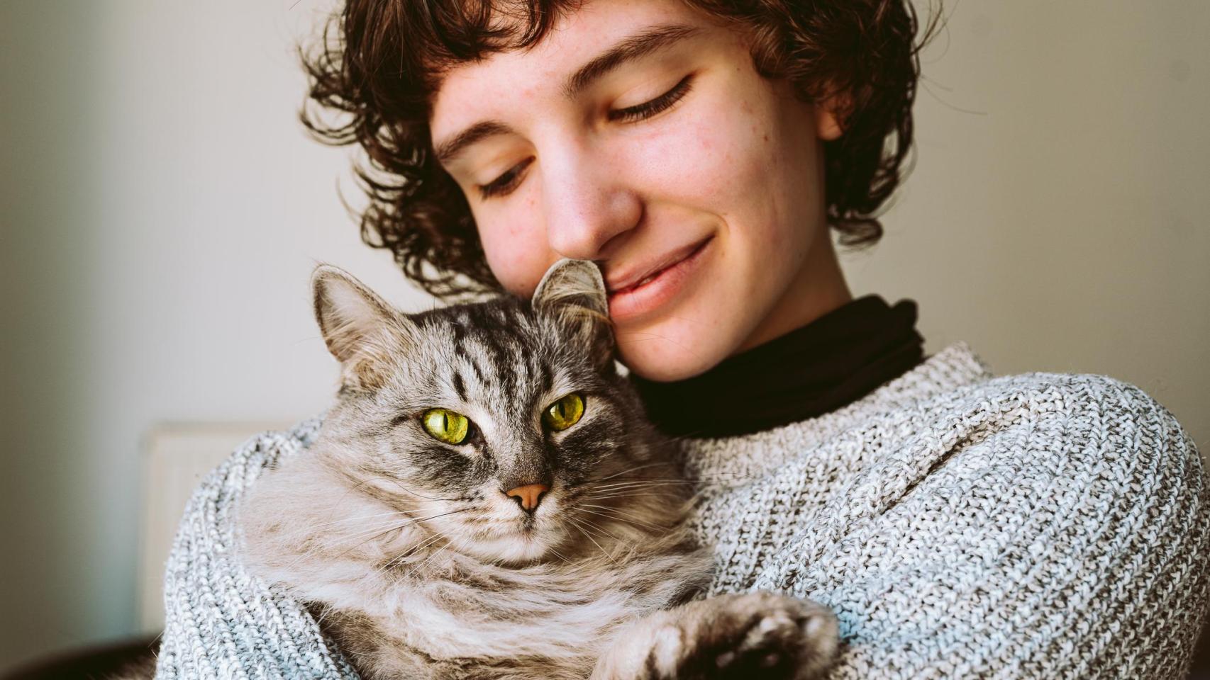 Una chica con un gato en brazos.