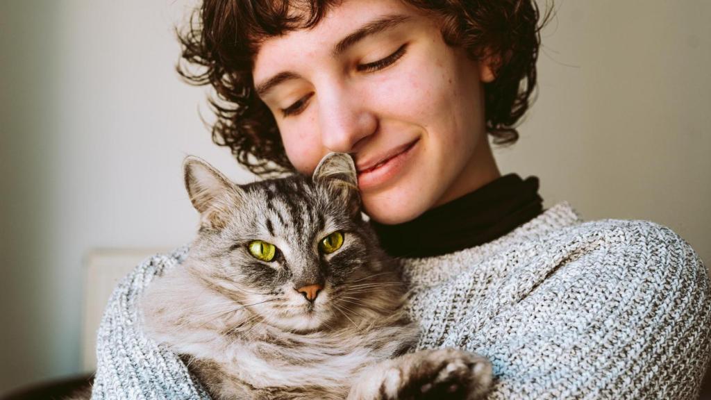 Una chica con un gato en brazos.