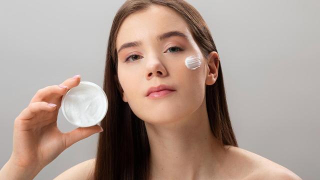 Mujer joven con un pote de crema en las manos.